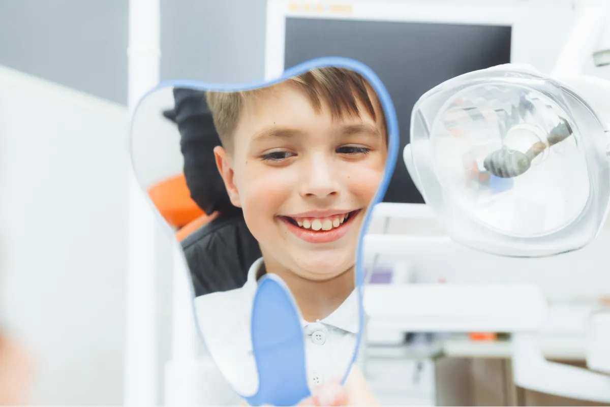 Boy admiring his smile in a dental mirror